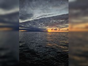 A breathtaking sunset over the ocean, with dramatic clouds reflecting on the water — a perfect backdrop for serene boating experiences.