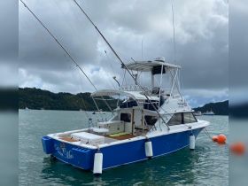 A striking view of the fishing boat 'Pasa Mas' anchored in calm waters, showcasing its sleek design and fishing gear — perfect for deep-sea adventures.