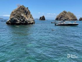 A vibrant scene of snorkelers enjoying the clear waters near rocky islands, with boats anchored nearby — perfect for a fun day of water activities.