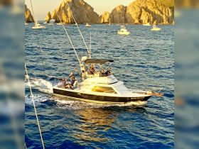 A group of anglers aboard a fishing boat in Cabo San Lucas, enjoying a day on the water with stunning rock formations in the background.