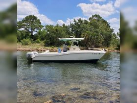 A center console boat is docked in calm waters surrounded by lush greenery, showcasing a perfect day for fishing or leisure on the water.