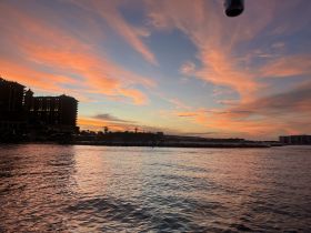A stunning sunset paints the sky with vibrant colors over the coastline, creating a picturesque backdrop for evening boat trips.