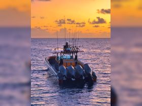 A striking sunset view of a fishing boat equipped with multiple rods, showcasing the perfect setting for an evening on the water.