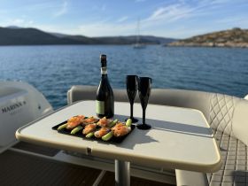 A beautifully arranged platter of smoked salmon on cucumber slices, paired with champagne and elegant glasses, perfect for a luxurious day on the water.
