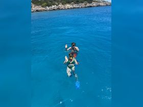 A couple enjoys snorkeling in crystal-clear blue waters, waving at the camera — a perfect moment of adventure and fun in the sun.