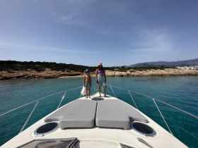 Two children enjoy the view from the bow of a boat, surrounded by stunning turquoise waters and a picturesque coastline — a perfect moment for family exploration on the water.