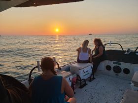 A group of friends enjoys a beautiful sunset on a boat, creating a perfect backdrop for memorable moments on the water.