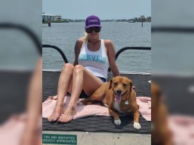 A woman relaxes on a boat with her dog, enjoying a sunny day on the water — a perfect moment for pet lovers and boating enthusiasts.