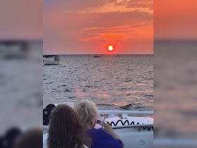 A couple enjoys a serene sunset view from their boat, capturing a romantic moment on the water. Perfect for sunset cruises and intimate getaways.