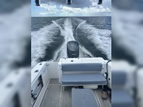 A view of the interior seating area of a boat, showcasing a comfortable bench and helm, perfect for enjoying a day on the water.