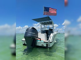 A striking view of a boat with an American flag flying, anchored in clear waters, showcasing its sleek design and inviting atmosphere for a day on the water.