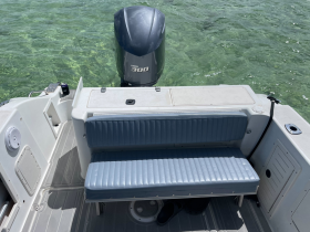 A clean and spacious interior view of a boat's seating area, featuring comfortable blue cushions and a Yamaha outboard motor in the background, perfect for relaxing on the water.