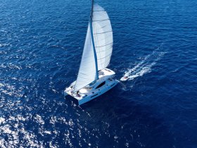A stunning aerial view of a catamaran sailing through deep blue waters, showcasing its elegant sails and sleek design — perfect for luxury sailing experiences.