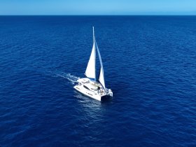 A stunning aerial view of a sailboat gracefully navigating through deep blue waters, showcasing the beauty of sailing adventures.
