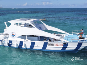 A sleek catamaran named 'Kimbarata Travel Tours' navigates through clear turquoise waters, showcasing its modern design and inviting atmosphere for adventure seekers.