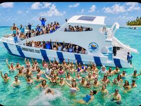 A vibrant group of guests enjoys a fun-filled day in the water with Kimbara Travel Tours, celebrating and swimming around their boat in a stunning tropical setting.
