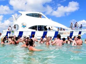 A lively group enjoys a fun day in the water around a tour boat, celebrating and socializing in the sun — perfect for unforgettable aquatic adventures.