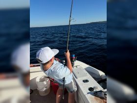 A young boy enjoys a fishing experience on a boat, casting his line into the open ocean — a perfect moment for family adventures on the water.