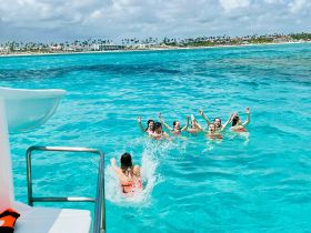A lively group of friends enjoys a splash in the crystal-clear waters, showcasing the fun and excitement of a day on the water.