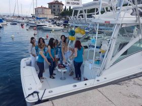 A lively group of women celebrates on a boat at the dock, showcasing a fun party atmosphere perfect for special occasions or gatherings on the water.