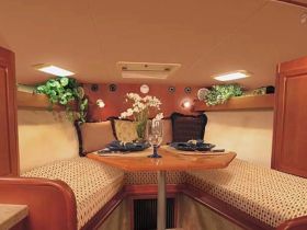 Cozy interior of a boat cabin featuring a dining area with plush seating and decorative plants, perfect for intimate meals on the water.