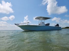 A striking view of a center console boat gliding through clear waters under a bright blue sky, perfect for fishing or leisure outings.