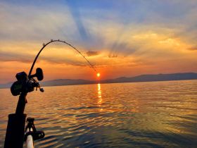 A stunning sunset view while fishing, with the fishing rod bent in anticipation of a catch — a perfect moment for anglers on the water.
