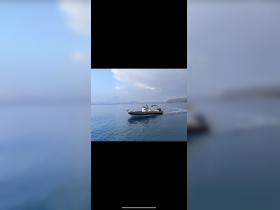A sleek speedboat glides through calm waters, showcasing its design and performance against a scenic backdrop.