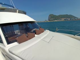 A cozy seating area on a yacht's deck, featuring plush cushions and a view of the coastline, perfect for relaxation while cruising.