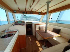 Interior view of a well-appointed boat cabin featuring a helm and comfortable seating, perfect for relaxing while cruising.