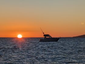 A serene silhouette of a boat against a stunning sunset, perfect for capturing the tranquil beauty of evening on the water.