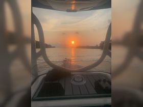 A serene sunset view from the deck of a boat, showcasing the tranquil waters and the warm glow of the setting sun — perfect for evening cruises.