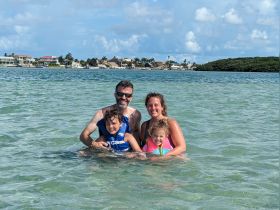 A joyful family enjoys a fun day swimming in shallow waters, creating lasting memories in a beautiful beach setting.
