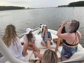A lively group of friends enjoys drinks and laughter aboard a boat, capturing the essence of a fun day on the water.