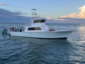 A group of people gather on the deck of the fishing boat 'Reelistic,' enjoying a day on the ocean — perfect for fishing adventures and group outings.