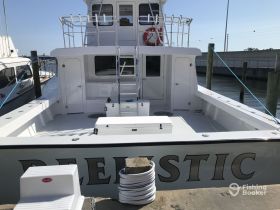 A clear view of the back deck of a yacht named 'Realistic', showcasing its spacious design and docked position.