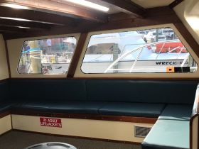 Interior view of a boat cabin featuring comfortable seating and a glimpse of the marina outside, ideal for relaxing before setting sail.