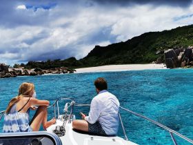A couple enjoys the stunning view of a secluded beach while relaxing on a boat, perfect for island hopping adventures in crystal-clear waters.