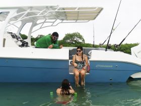 A family enjoys a fun day on the water, with one child swimming and adults relaxing on the boat — perfect for fishing trips and family outings.