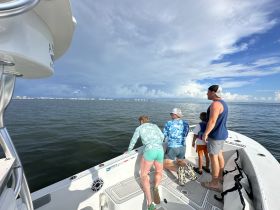 A family group leans over the side of a boat, enjoying a fishing trip on the ocean, showcasing the excitement of a day on the water.