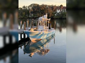 A stunning view of a blue boat docked at sunset, reflecting beautifully on the calm waters — perfect for fishing or leisurely cruises.