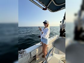 A joyful angler proudly displays her catch while enjoying a day of fishing on the open ocean — a perfect snapshot of adventure and fun on the water.