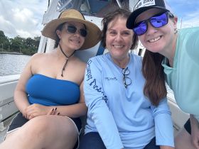 Three friends enjoy a sunny day on a boat, capturing a joyful moment together — perfect for memorable outings and adventures on the water.