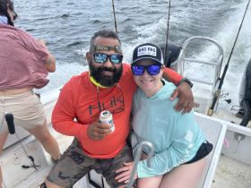 A joyful moment captured on a fishing trip, showcasing friends enjoying their time on the water with smiles and drinks.