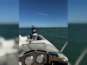 A young boy enjoys a day on the water, casting a line from the boat into the ocean — a perfect moment for family fishing adventures.