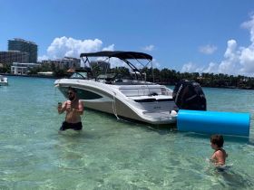A man and a child enjoy a sunny day in the water near a boat, capturing fun moments and family bonding in a vibrant aquatic setting.