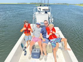 A joyful family enjoys a day on the water, with kids wearing life jackets and having fun aboard a fishing boat — perfect for creating lasting memories on family outings.