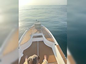 A serene view from the front of a boat, showcasing a calm sea and a cooler, perfect for a relaxing day on the water.
