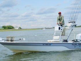 A fisherman navigates a sleek boat on the water, showcasing the thrill of fishing adventures. Perfect for those seeking an exciting day on the water.