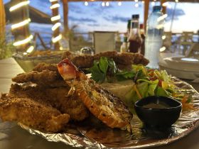 A delicious seafood platter featuring grilled lobster and crispy fish, perfect for enjoying a meal during a boating trip or seaside dining experience.